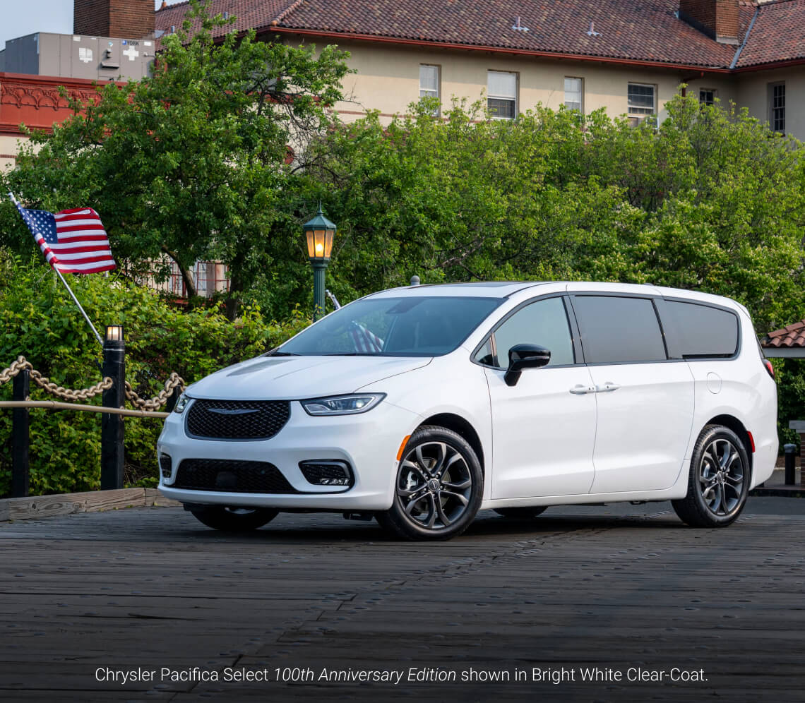 Front three-quarter view of a 2026 Chrysler Pacifica Select 100th Anniversary Edition in Bright White Clear-Coat parked on a wooden pier.