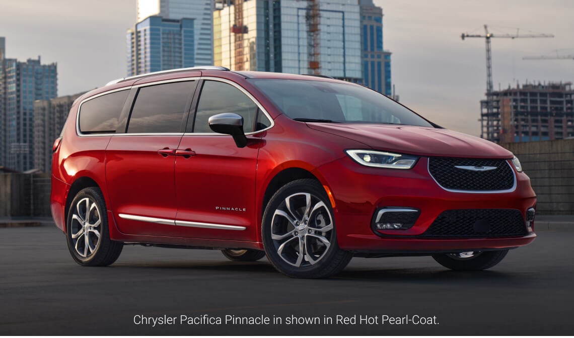 Front three-quarter view of a 2026 Chrysler Pacifica Pinnacle in Red Hot Pearl-Coat parked in an urban environment.