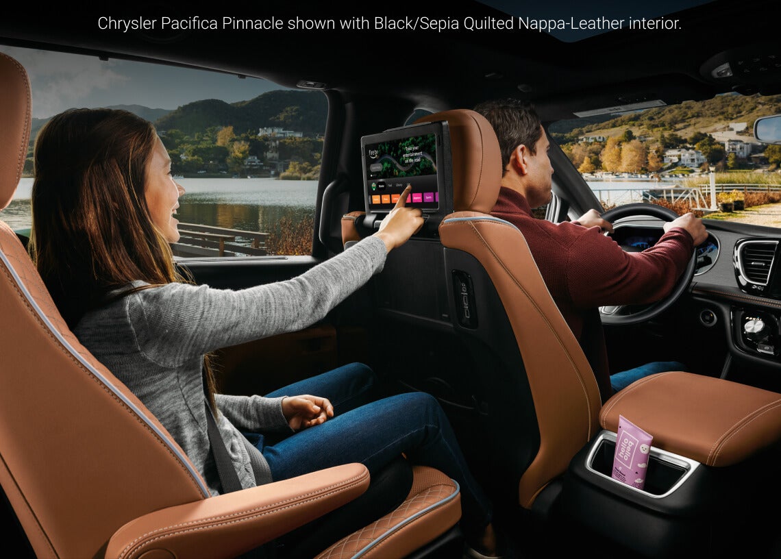 Interior view of rear seat passenger using seatback Fire TV entertainment screen in a 2026 Chrysler Pacifica Pinnacle with Sepia Quilted Nappa leather.