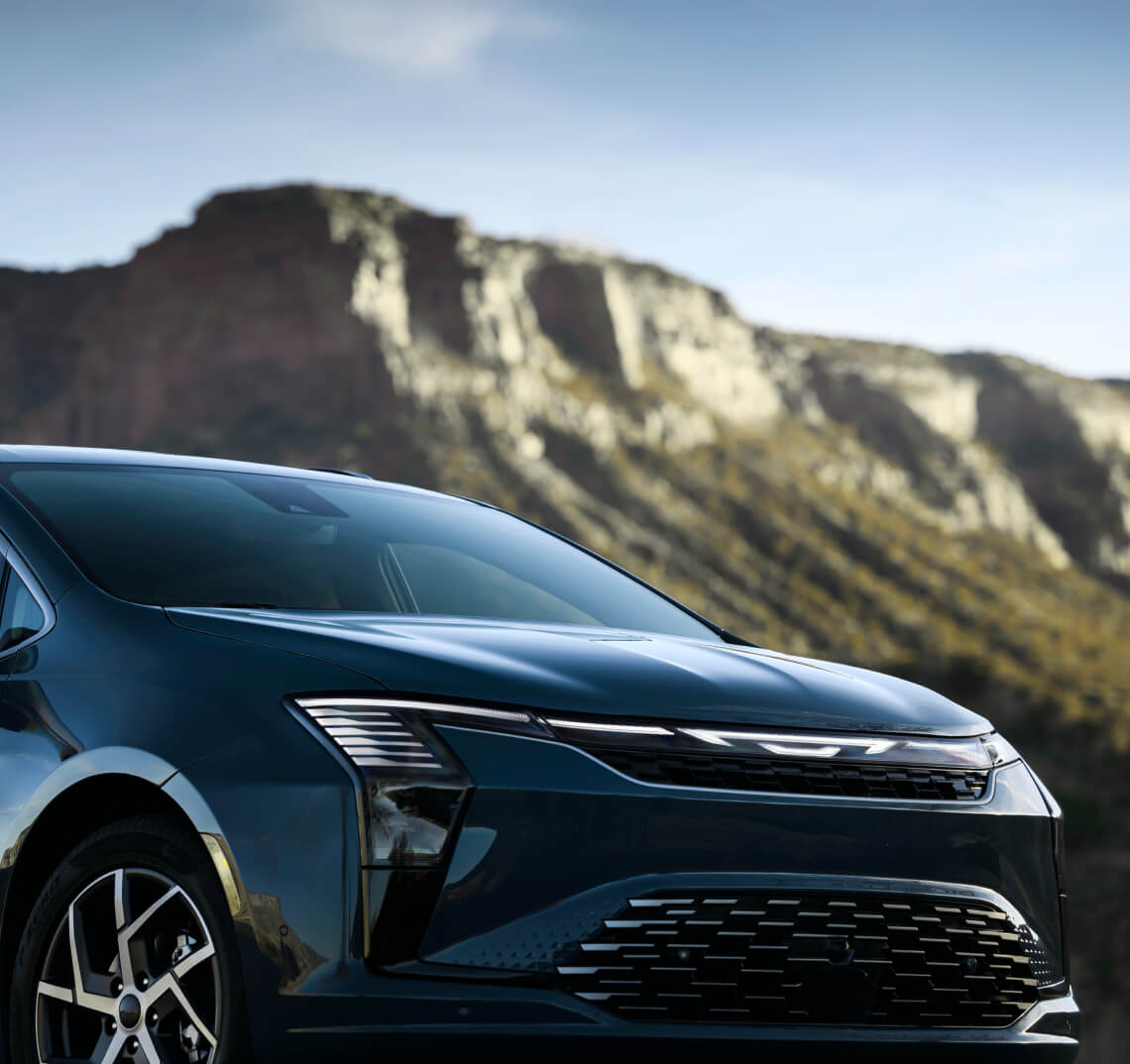 Close-up front view of a blue 2027 Chrysler Pacifica Pinnacle with a rocky mountain backdrop.