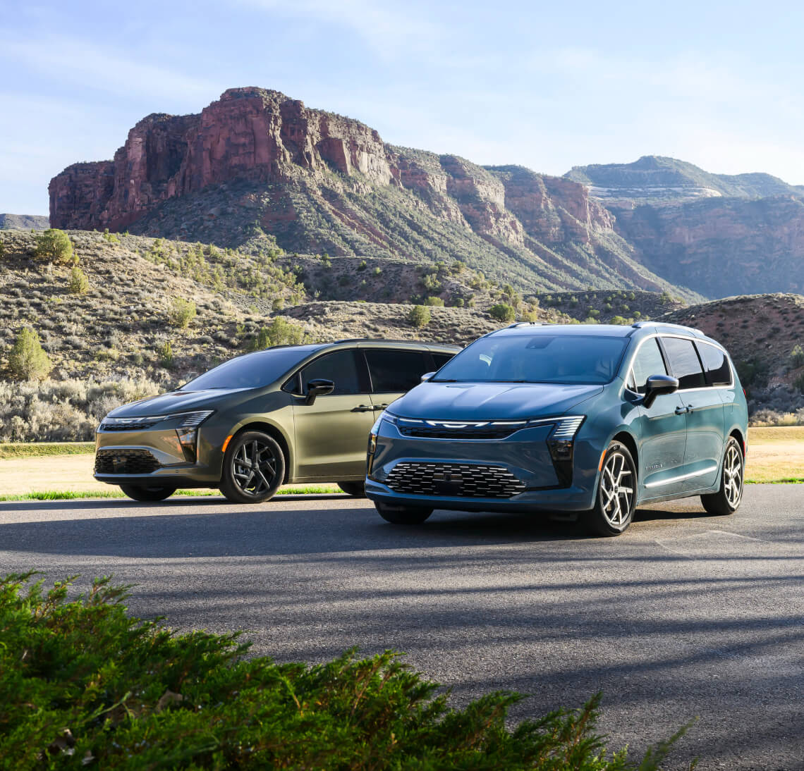 Front-angled view of a green and blue 2027 Chrysler Pacifica parked near rocky mountains.
